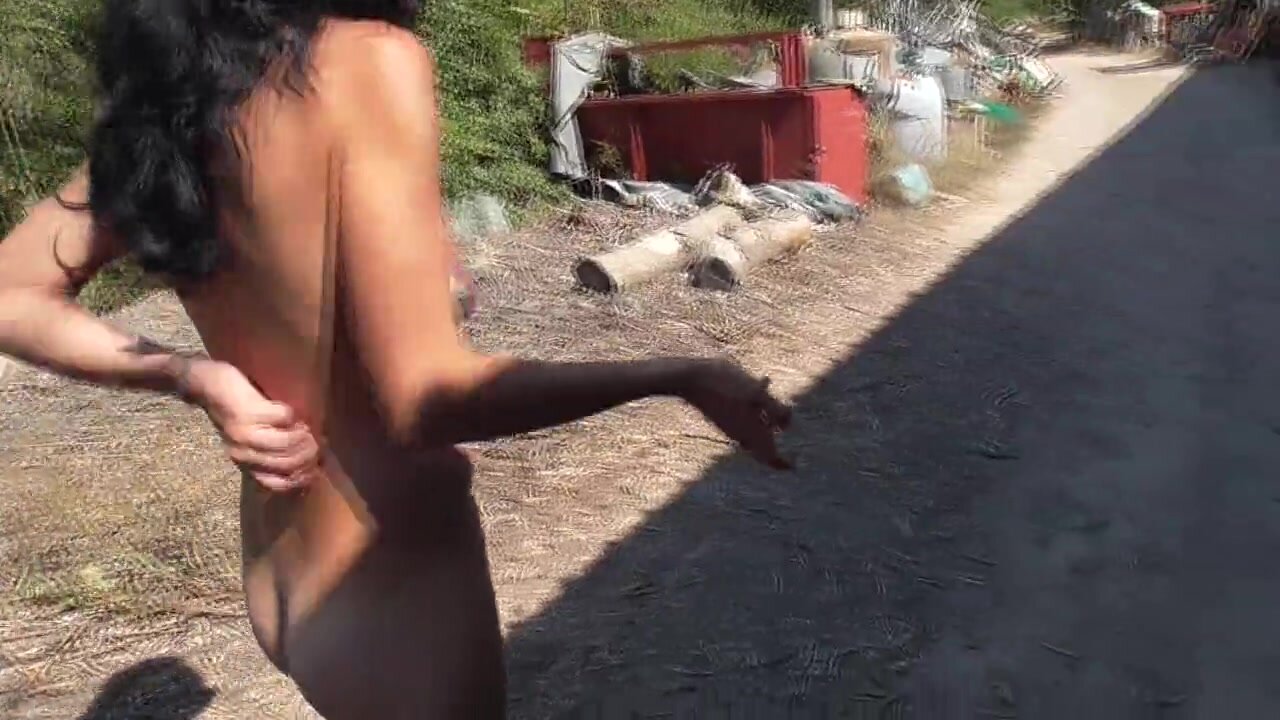 Exhibitionist nudist woman walking on road close to the beach